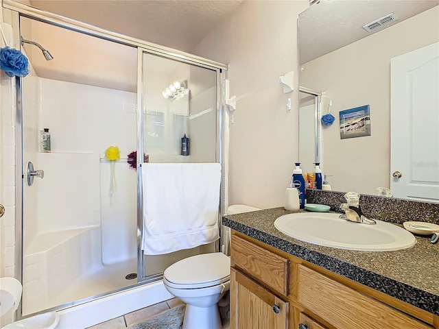 bathroom with vanity, a shower with shower door, toilet, and tile patterned flooring