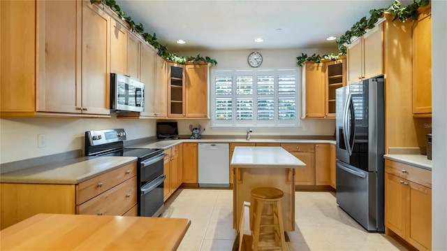 kitchen with a center island, appliances with stainless steel finishes, a kitchen bar, and light brown cabinets