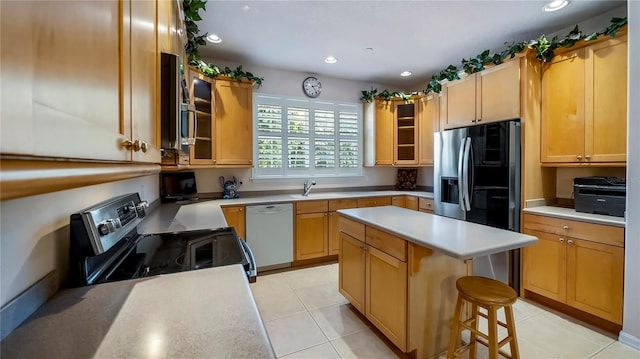 kitchen with a center island, stainless steel appliances, a kitchen bar, and light tile patterned floors