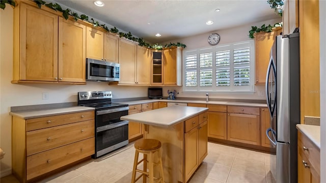 kitchen featuring light tile patterned floors, appliances with stainless steel finishes, a breakfast bar area, sink, and a center island