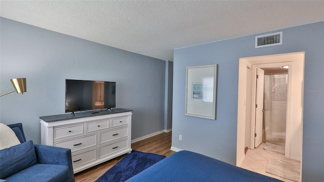 145 N Halifax Ave Unit 711, Daytona Beach, FL 32118 - bedroom with ensuite bathroom, a textured ceiling, and light wood-type flooring