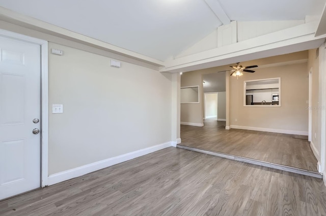 empty room featuring ceiling fan, vaulted ceiling with beams, and light hardwood / wood-style flooring