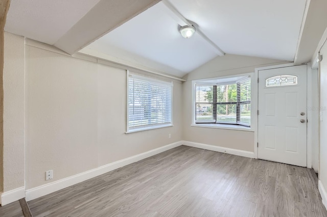 entryway with light wood-type flooring and lofted ceiling with beams