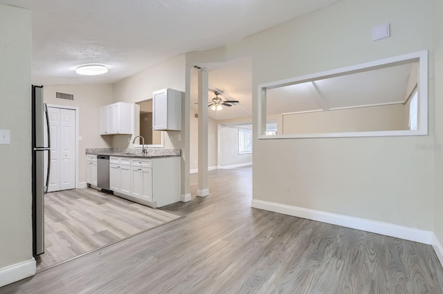 kitchen featuring light wood-type flooring, appliances with stainless steel finishes, sink, white cabinets, and ceiling fan