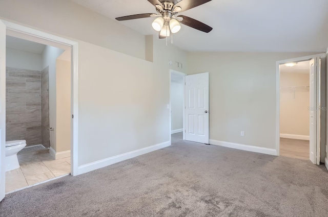 unfurnished bedroom with ceiling fan, connected bathroom, a spacious closet, and light colored carpet