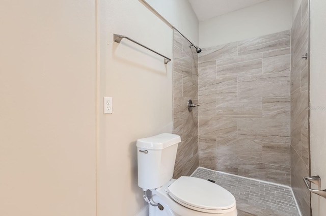 bathroom featuring tiled shower and toilet