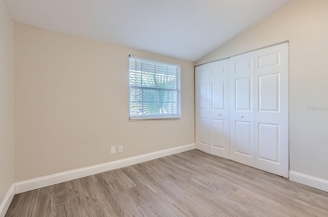 unfurnished bedroom with a closet, lofted ceiling, and light hardwood / wood-style flooring