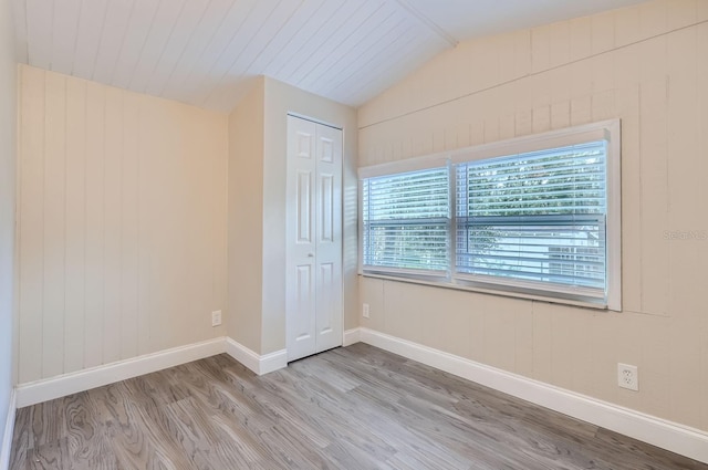 empty room with light wood-type flooring and lofted ceiling