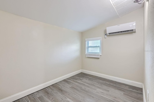 unfurnished room featuring lofted ceiling, wood-type flooring, and a wall mounted AC