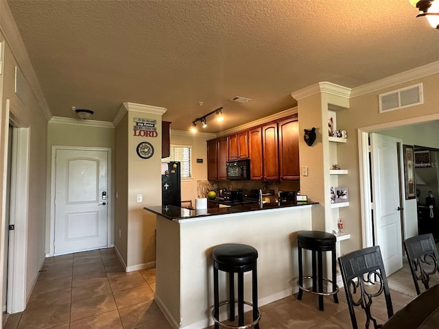 kitchen featuring kitchen peninsula, ornamental molding, black appliances, and a breakfast bar