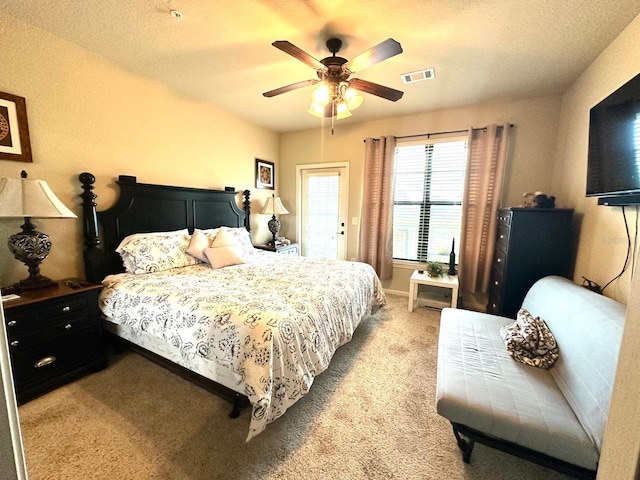 bedroom featuring ceiling fan, light carpet, and a textured ceiling