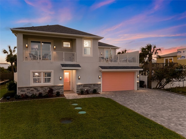 view of front of house with a balcony, a garage, and a lawn