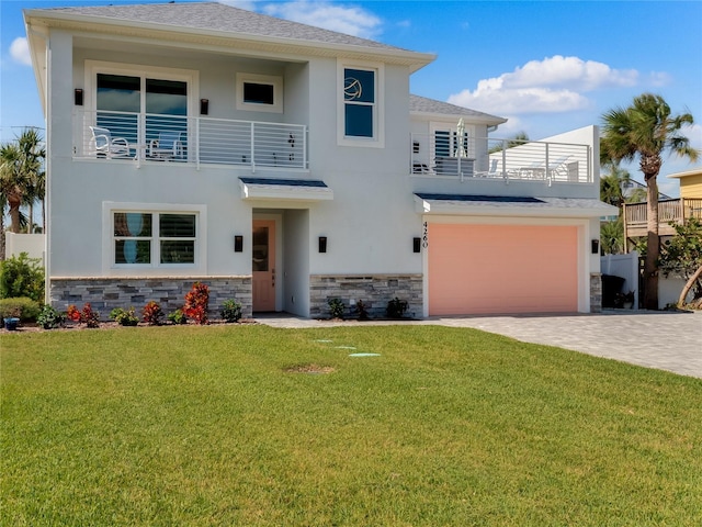 view of front of property with a garage, a balcony, and a front lawn