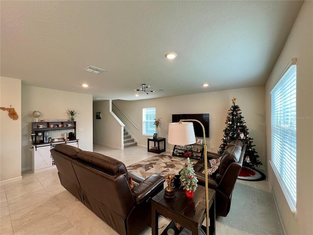 living room featuring a textured ceiling, stairway, visible vents, and recessed lighting