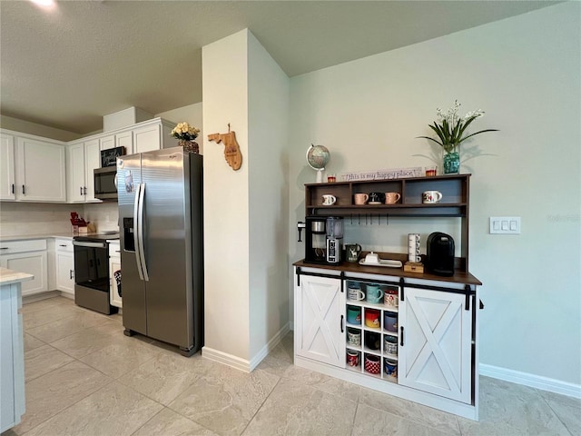 kitchen featuring stainless steel appliances, light countertops, white cabinets, and baseboards