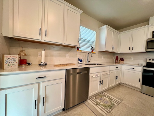 kitchen featuring stainless steel appliances, light countertops, backsplash, white cabinetry, and a sink