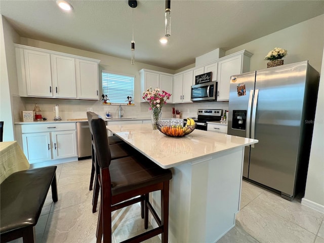 kitchen featuring hanging light fixtures, white cabinetry, stainless steel appliances, and a center island