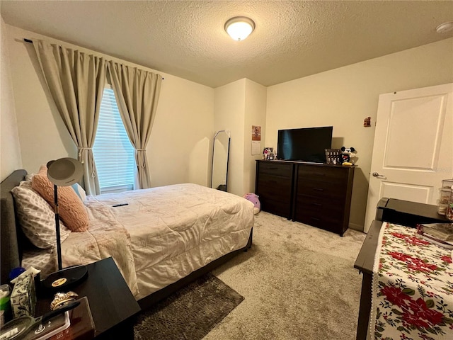 bedroom with light colored carpet and a textured ceiling