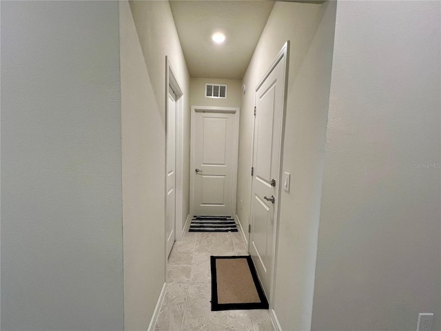 hallway featuring baseboards and visible vents