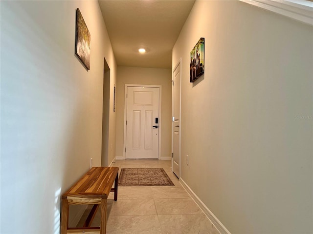 hallway with light tile patterned floors and baseboards