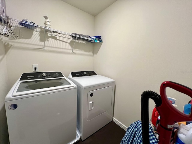 washroom featuring laundry area, baseboards, and washer and clothes dryer