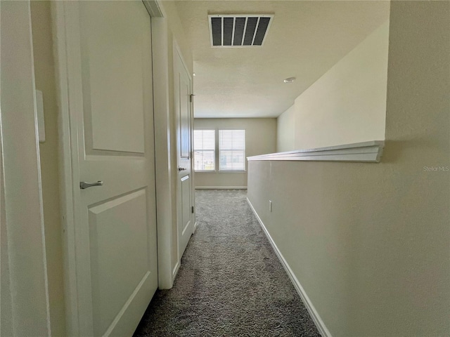 hall with baseboards, visible vents, and carpet flooring