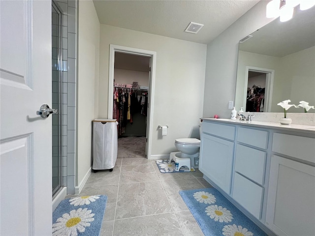 bathroom with a textured ceiling, tile patterned floors, vanity, toilet, and walk in shower