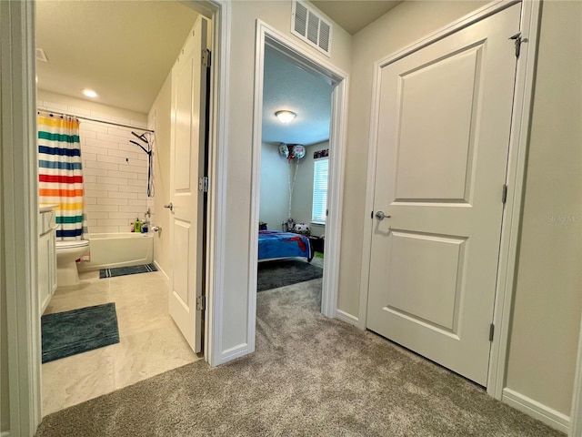 hall featuring carpet flooring, visible vents, and baseboards