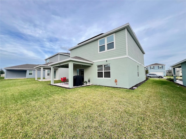 rear view of property featuring a yard, a patio area, and stucco siding