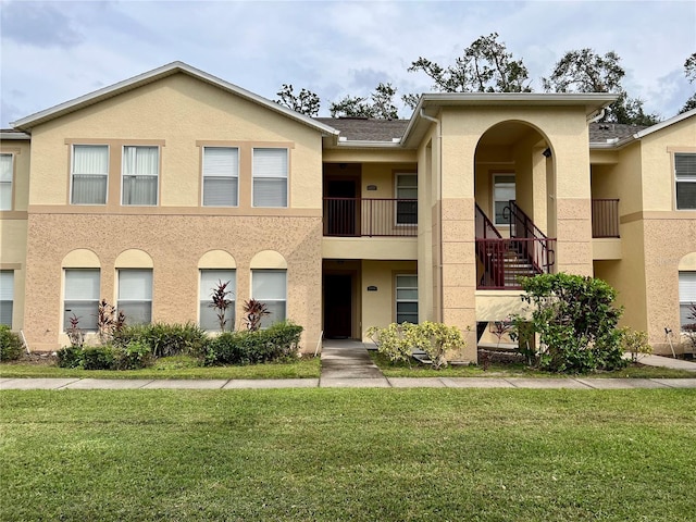 view of front of house featuring a front yard and a balcony