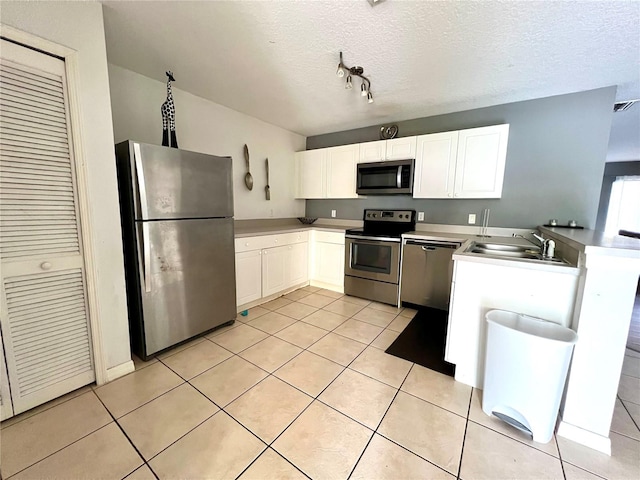 kitchen featuring appliances with stainless steel finishes, a textured ceiling, white cabinets, and sink