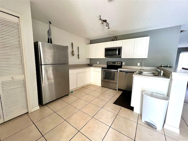 2878 Club Cortile Cir Unit A, Kissimmee, FL 34746 - kitchen with white cabinets, appliances with stainless steel finishes, a sink, a peninsula, and light tile patterned floors
