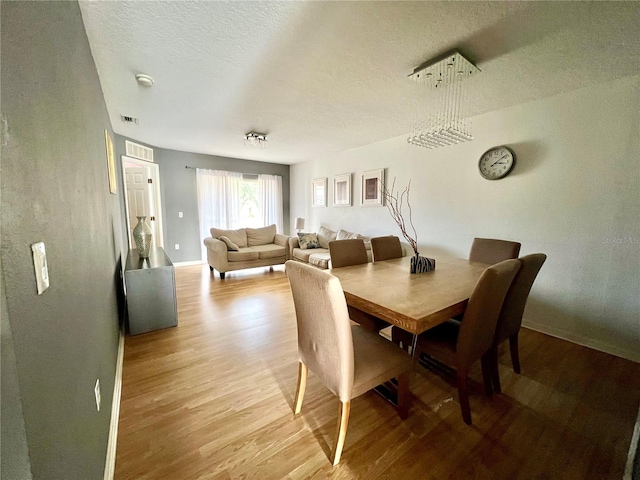 dining area featuring light hardwood / wood-style flooring and a textured ceiling