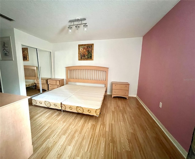 bedroom with hardwood / wood-style floors, a closet, and a textured ceiling