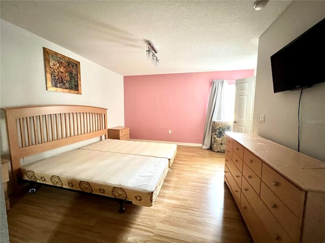 bedroom with a textured ceiling and light hardwood / wood-style floors