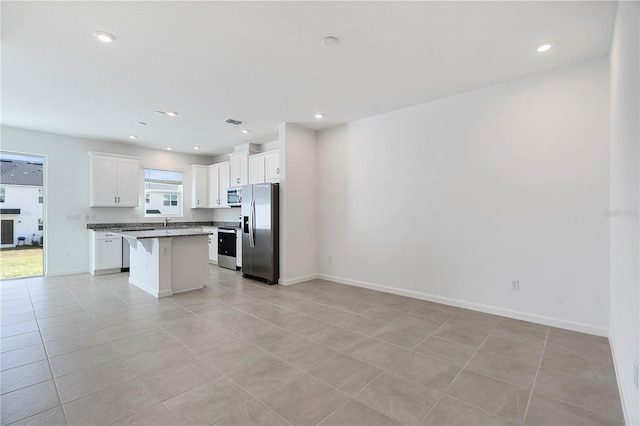 kitchen with light tile patterned flooring, a center island, white cabinetry, stainless steel appliances, and a breakfast bar