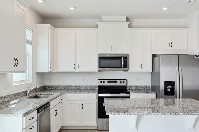 kitchen featuring white cabinetry, stainless steel appliances, sink, and light stone counters