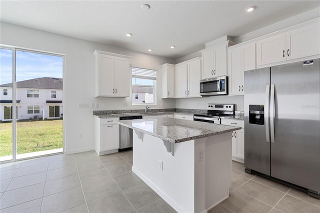 kitchen with a center island, white cabinets, a healthy amount of sunlight, and stainless steel appliances