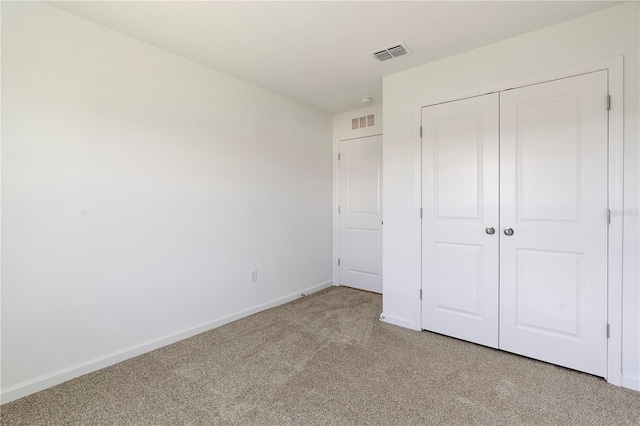 unfurnished bedroom with a closet and light colored carpet