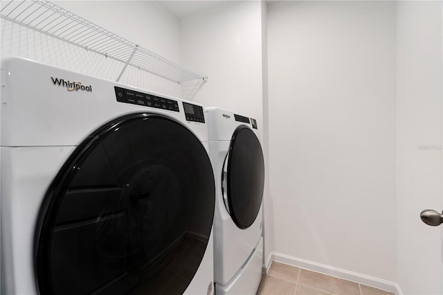 laundry area with washer and clothes dryer and light tile patterned floors