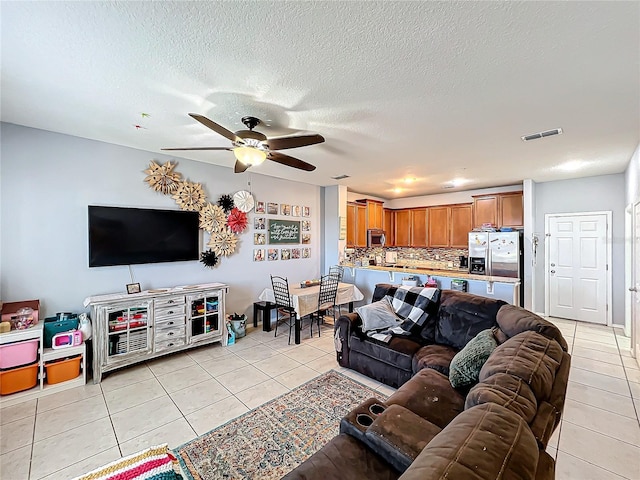 living room featuring a textured ceiling, ceiling fan, and light tile patterned floors