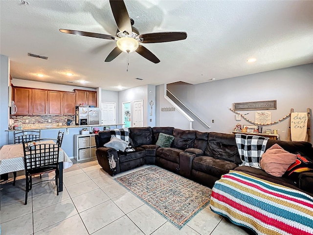 tiled living room with ceiling fan and a textured ceiling