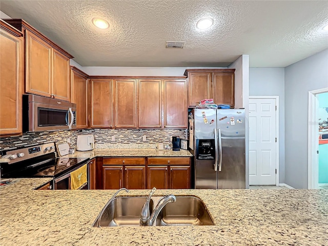 kitchen featuring sink, appliances with stainless steel finishes, decorative backsplash, and a textured ceiling