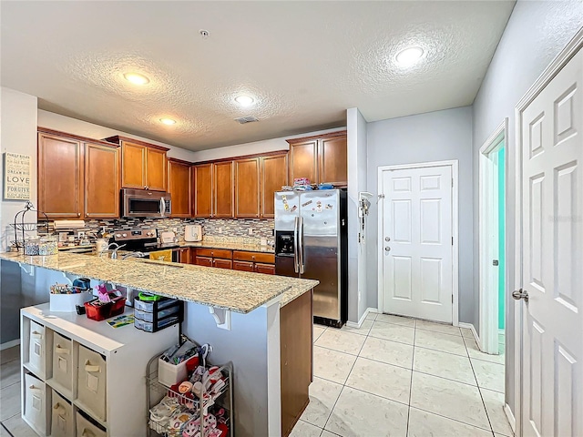 kitchen with a kitchen bar, a textured ceiling, kitchen peninsula, and stainless steel appliances