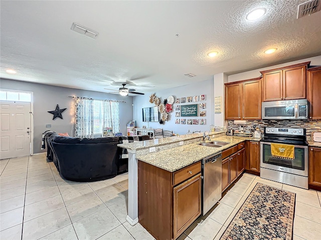 kitchen with kitchen peninsula, stainless steel appliances, sink, a textured ceiling, and ceiling fan