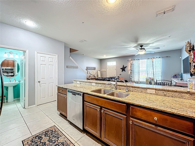 kitchen with sink, dishwasher, light stone counters, and a textured ceiling