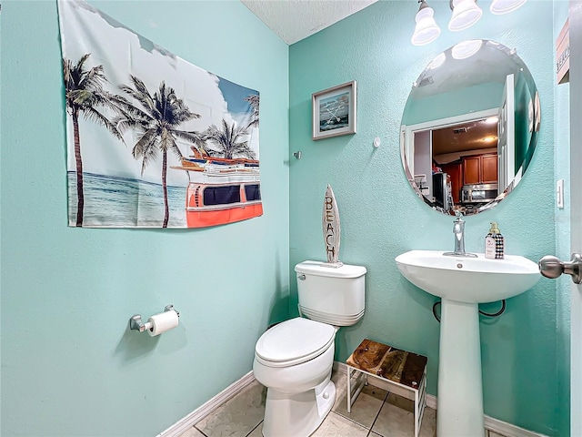 bathroom with a textured ceiling, toilet, and tile patterned flooring