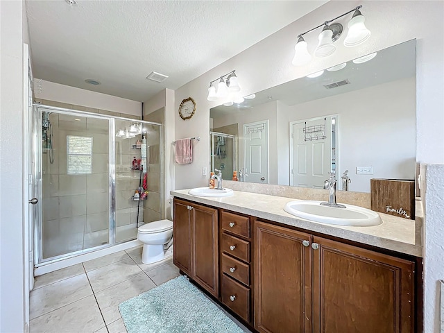 bathroom with a shower with door, a textured ceiling, toilet, vanity, and tile patterned flooring