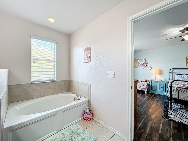 bathroom featuring a tub to relax in, hardwood / wood-style flooring, and ceiling fan