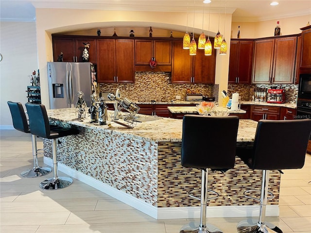 kitchen featuring light stone counters, crown molding, black appliances, decorative light fixtures, and a center island with sink